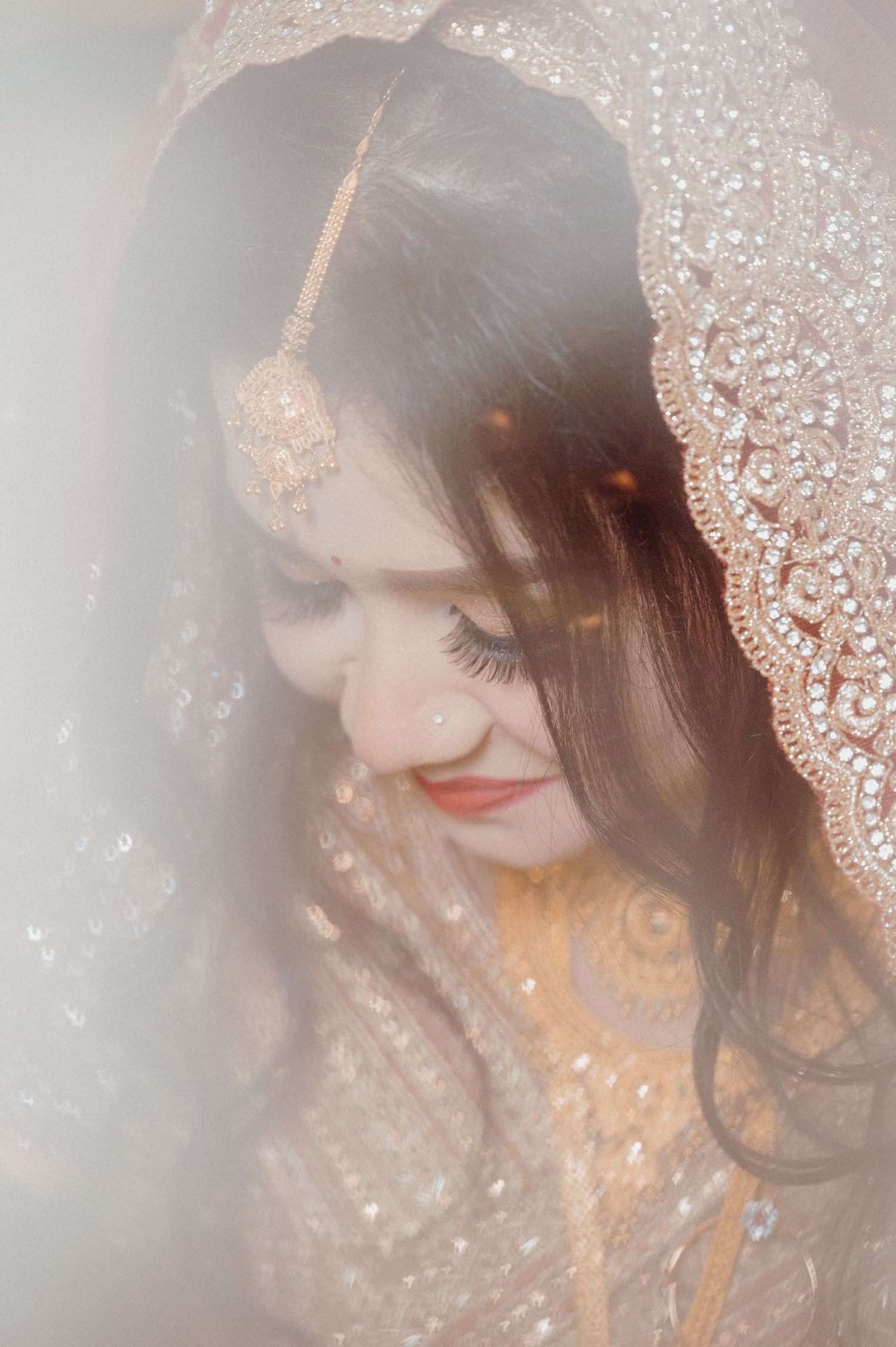 Ethereal bridal portrait with delicate lace veil detail and soft lighting.