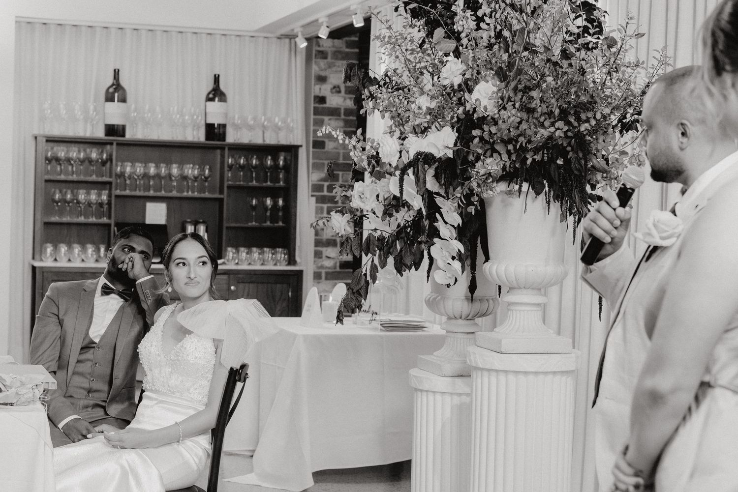 Black and white photo of wedding reception with elegant decor and bar backdrop.