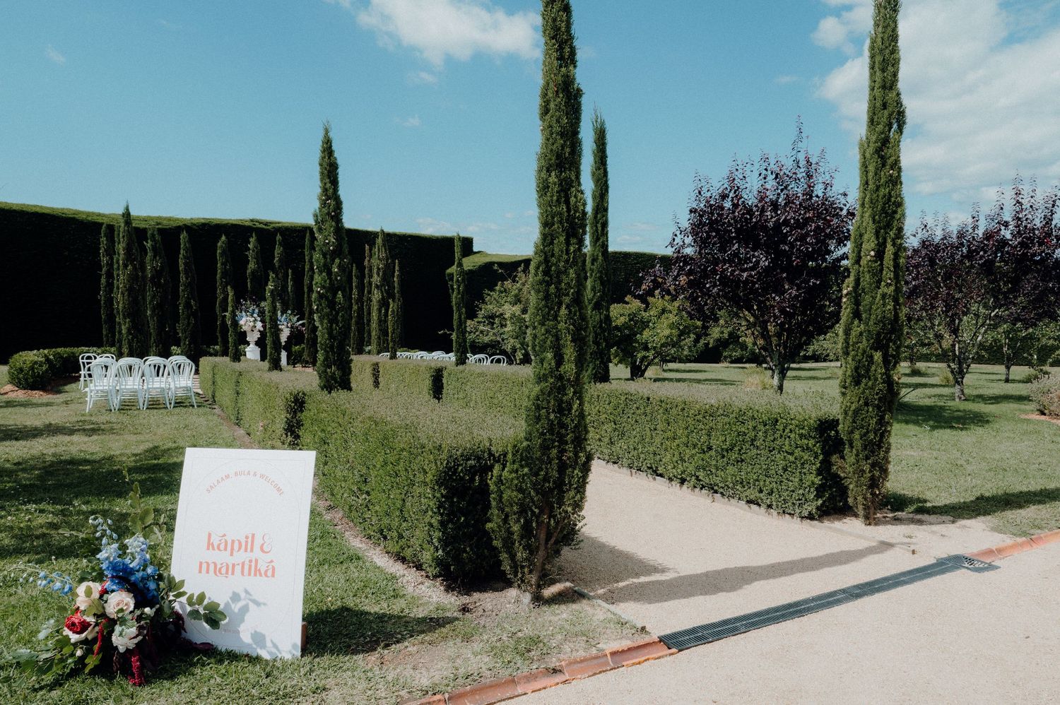 Elegant garden walkway lined with tall cypress trees and wedding decor.