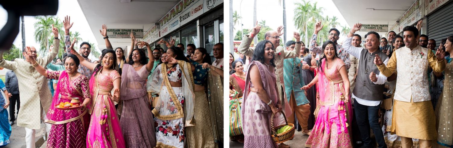 Wedding guests in vibrant pink and purple traditional attire dance and celebrate during a joyous ceremony.