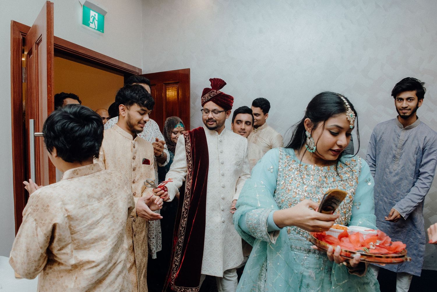Guests participate in wedding traditions exchanging gifts in a decorated hallway.