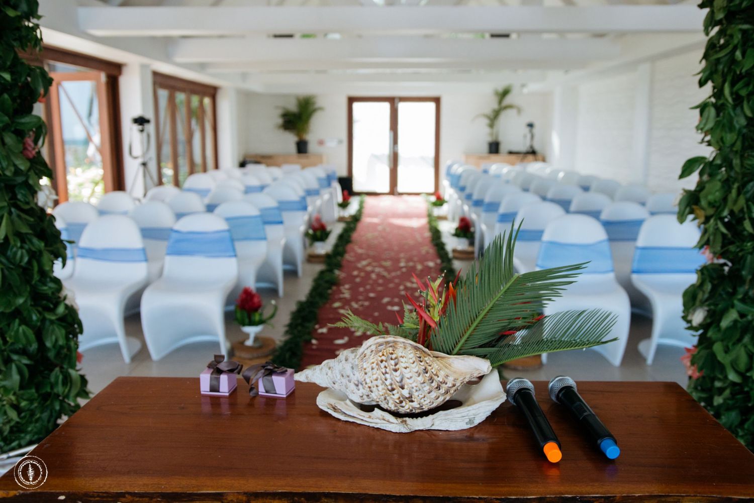 Wedding ceremony setup with blue chair sashes and palm leaf decor on a wooden table.