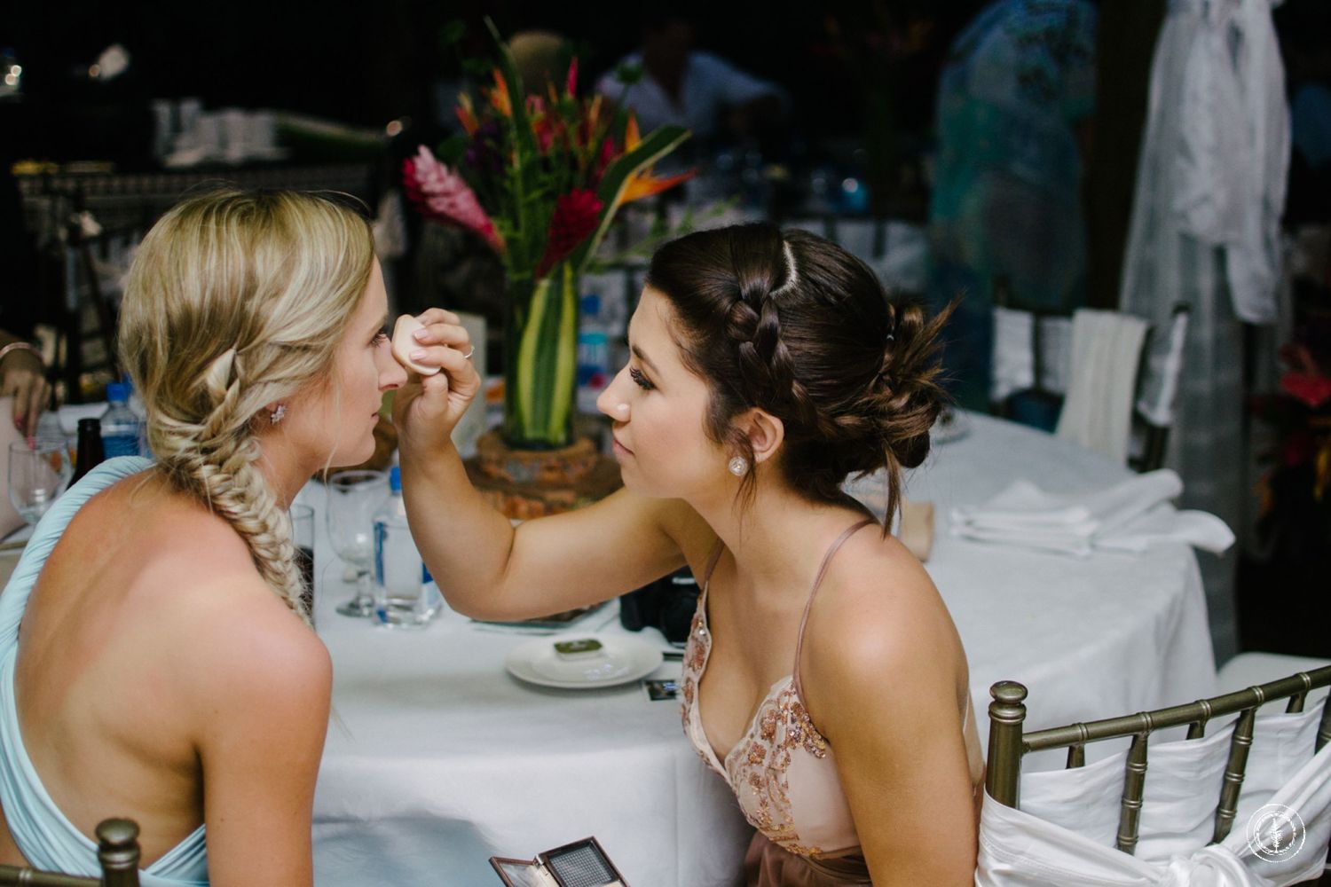Two guests share an intimate moment at an outdoor wedding reception with floral decorations.
