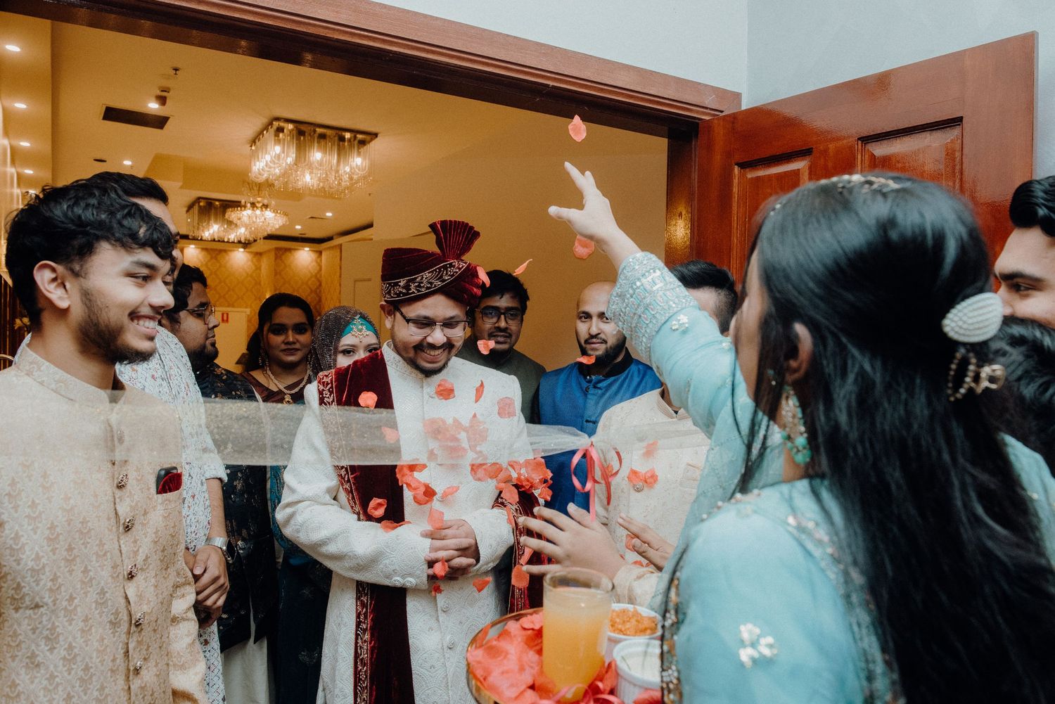 Wedding guests engage in festive celebrations with balloons and drinks in a decorated indoor space.