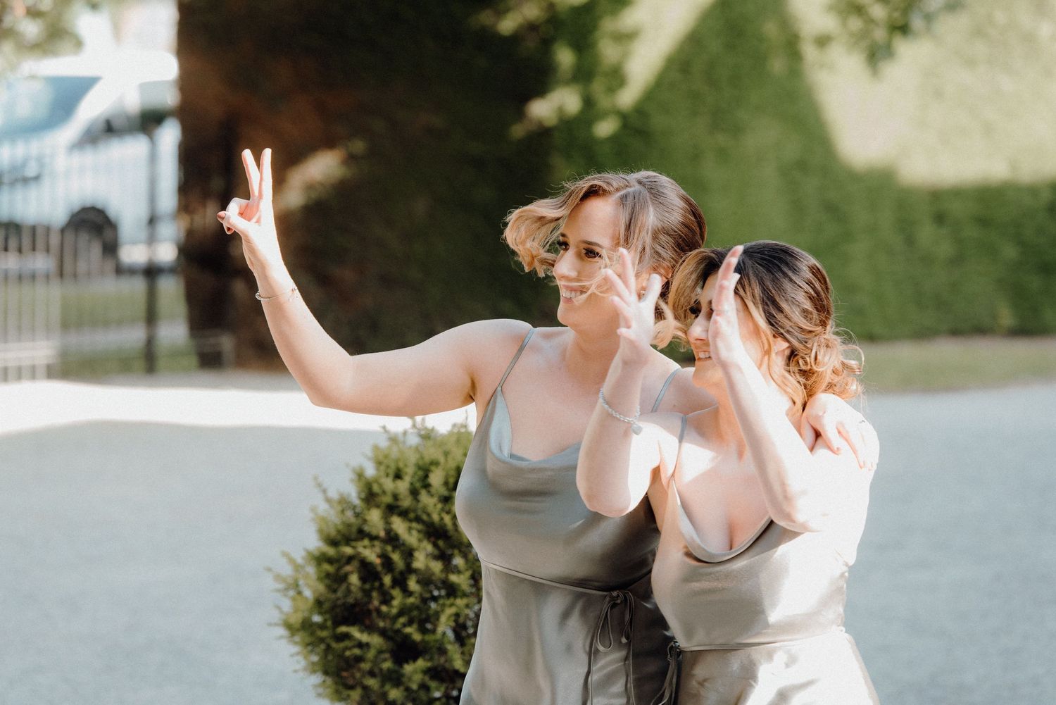 Three people in matching gray dresses pose together outdoors at a wedding.