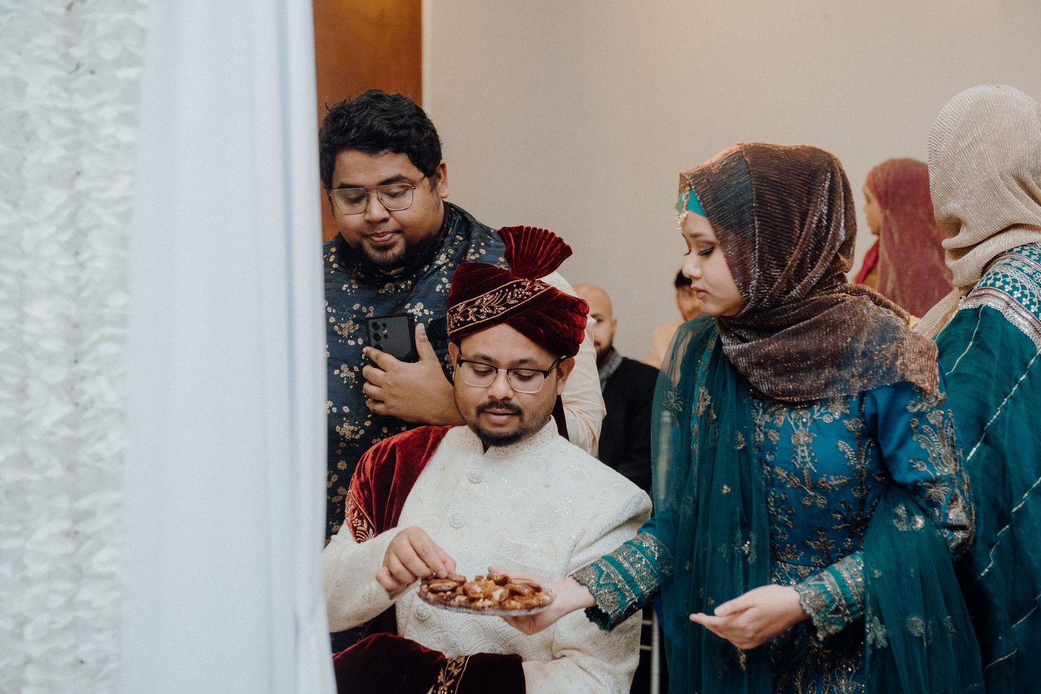 Wedding guests serving traditional snacks during a cultural ceremony.