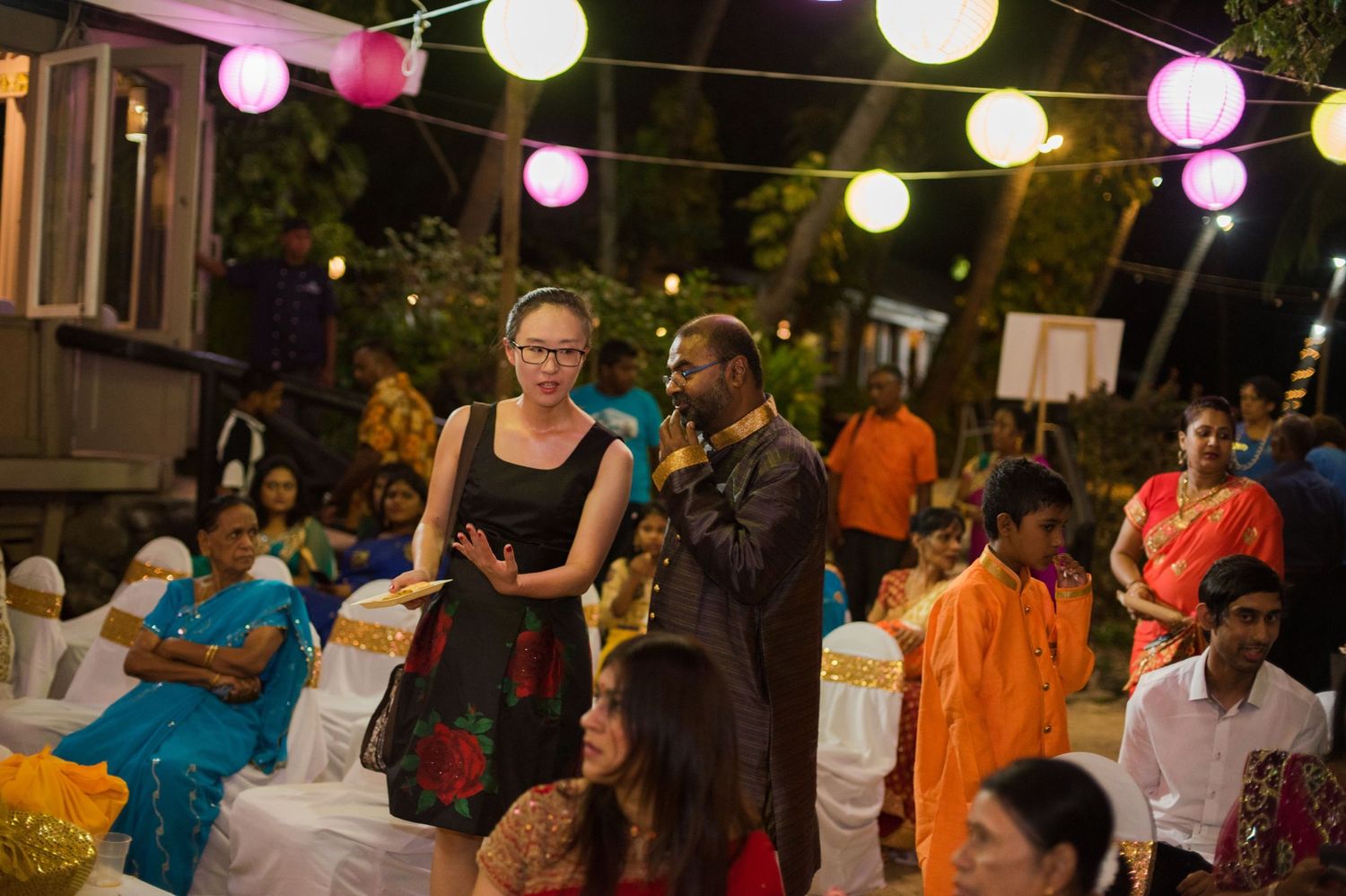 Guests enjoying an outdoor evening celebration with colorful lantern decorations.