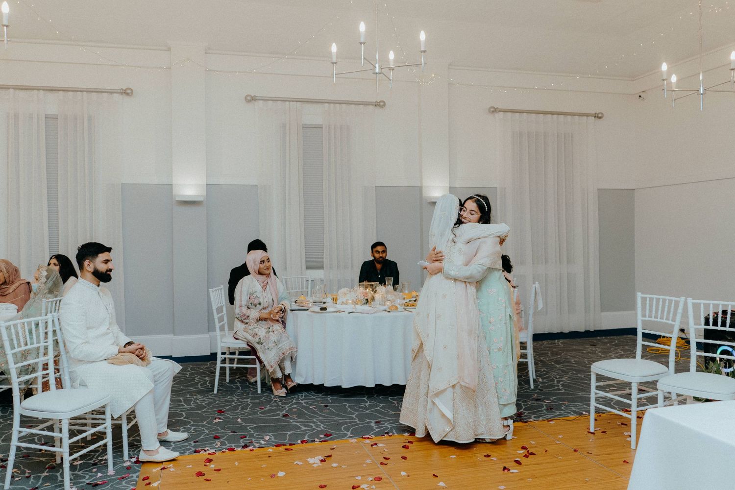 Wedding reception scene with guests seated at tables while someone delivers a speech.