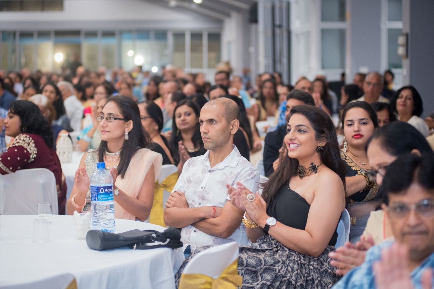 Engaged audience members watching and applauding during event presentation.