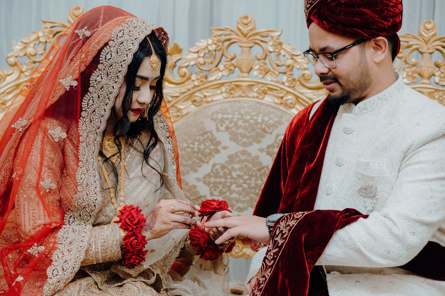 Traditional ring exchange ceremony taking place on an elegantly decorated golden throne.