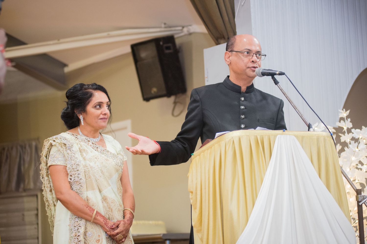 Speaker at podium addresses audience during formal event.