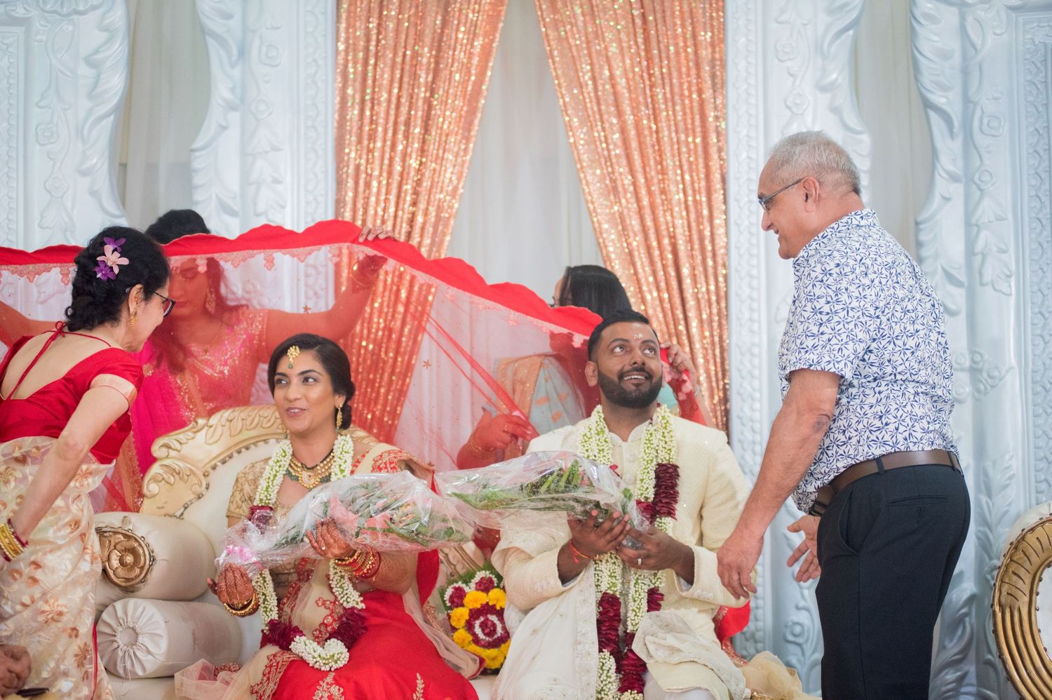 A traditional Indian wedding ceremony with decorative peach curtains and ornate seating arrangements.