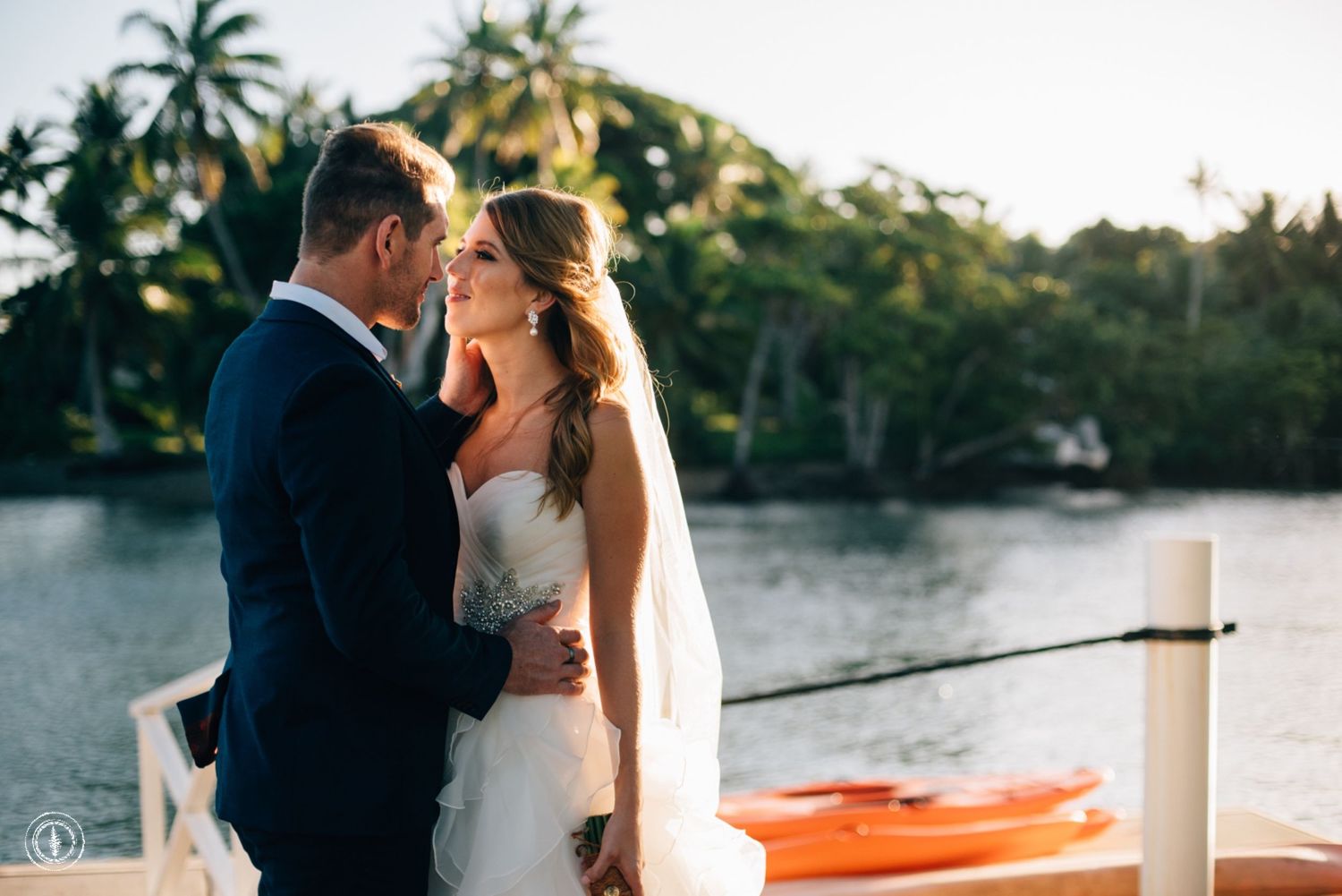 Intimate waterfront moment with palm trees and kayaks in the background.