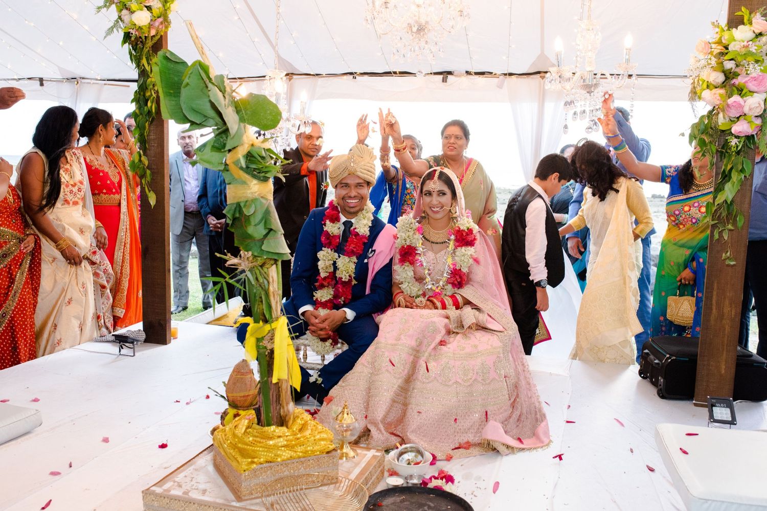 Wedding ceremony in a decorated tent with guests gathered around the couple.