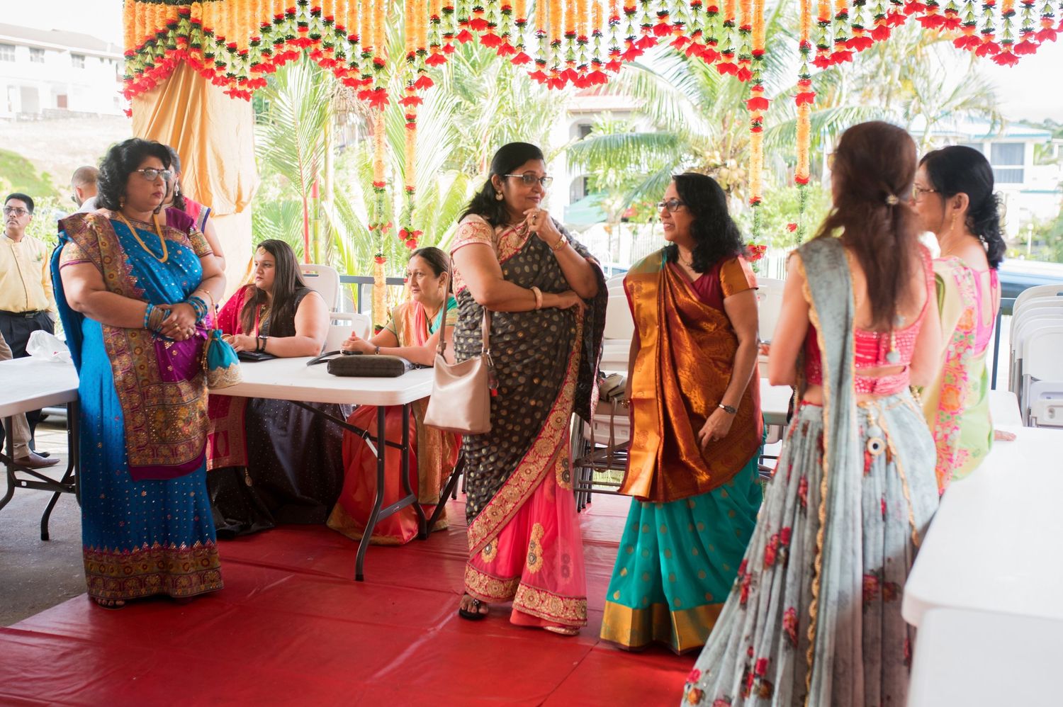 Guests in colorful saris gathered at decorated indoor venue during Indian wedding celebration.