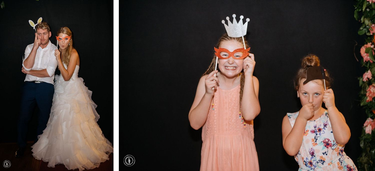 Wedding party guests pose with fun props and accessories against a floral backdrop.