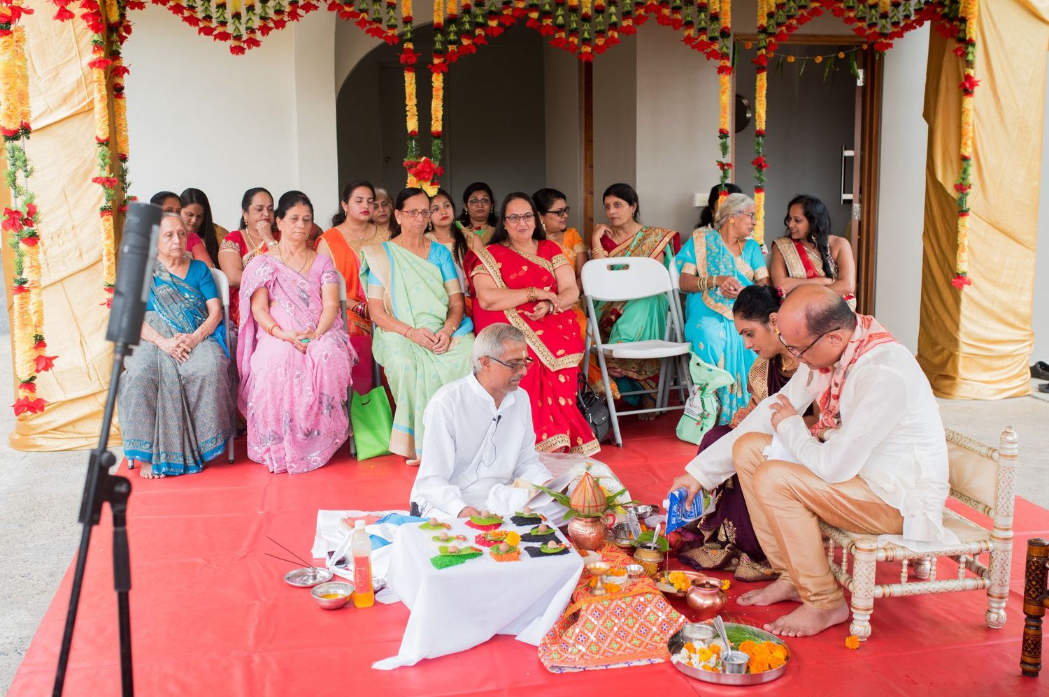 Traditional Indian wedding ceremony with guests seated watching priests perform rituals.