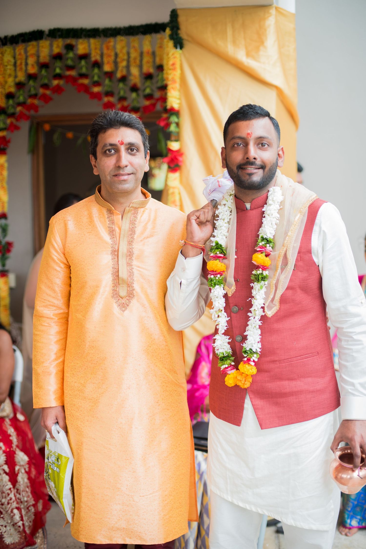 Two participants in traditional Indian attire standing beneath floral decorations.
