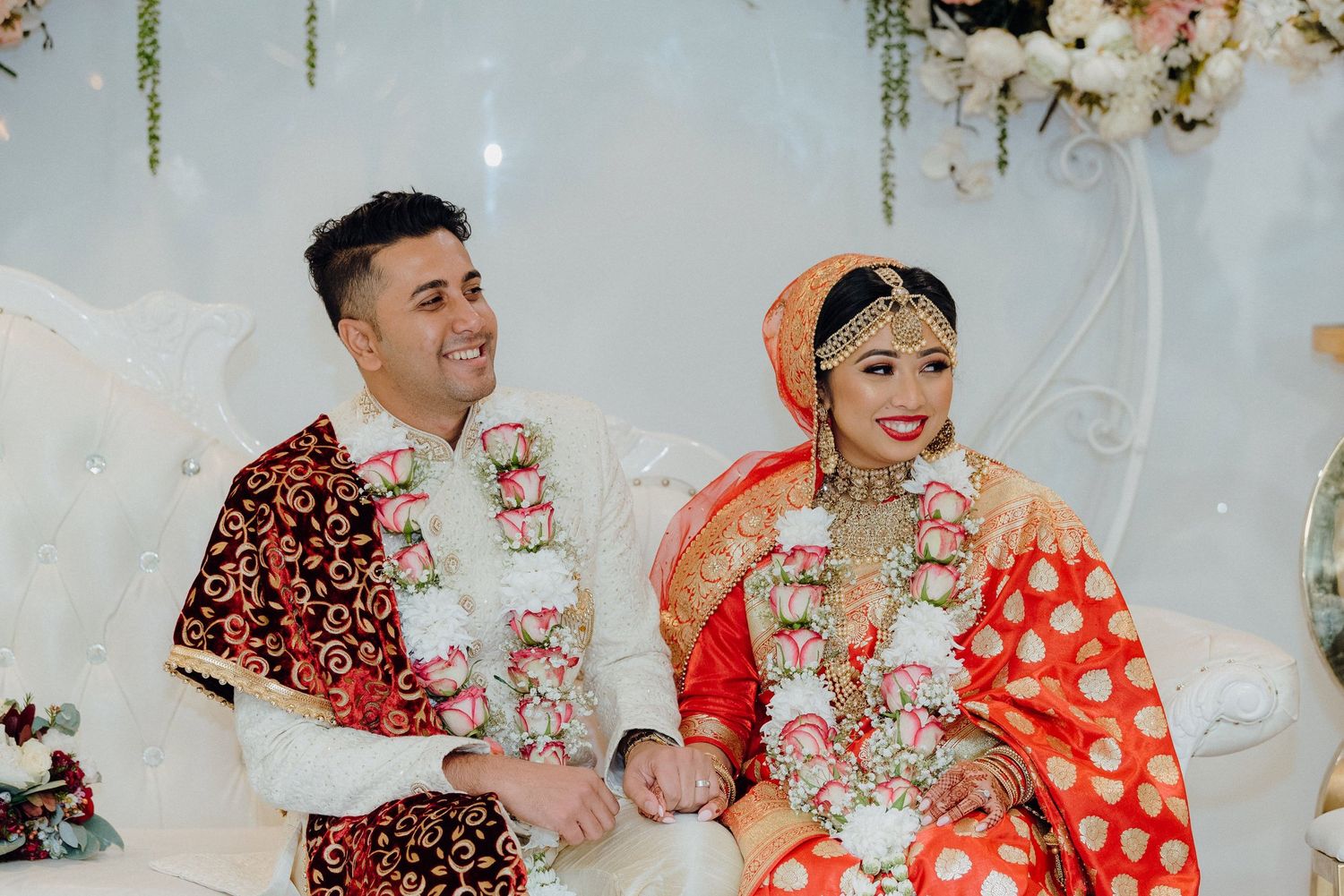 A couple in traditional wedding attire sharing a joyful moment during their ceremony.