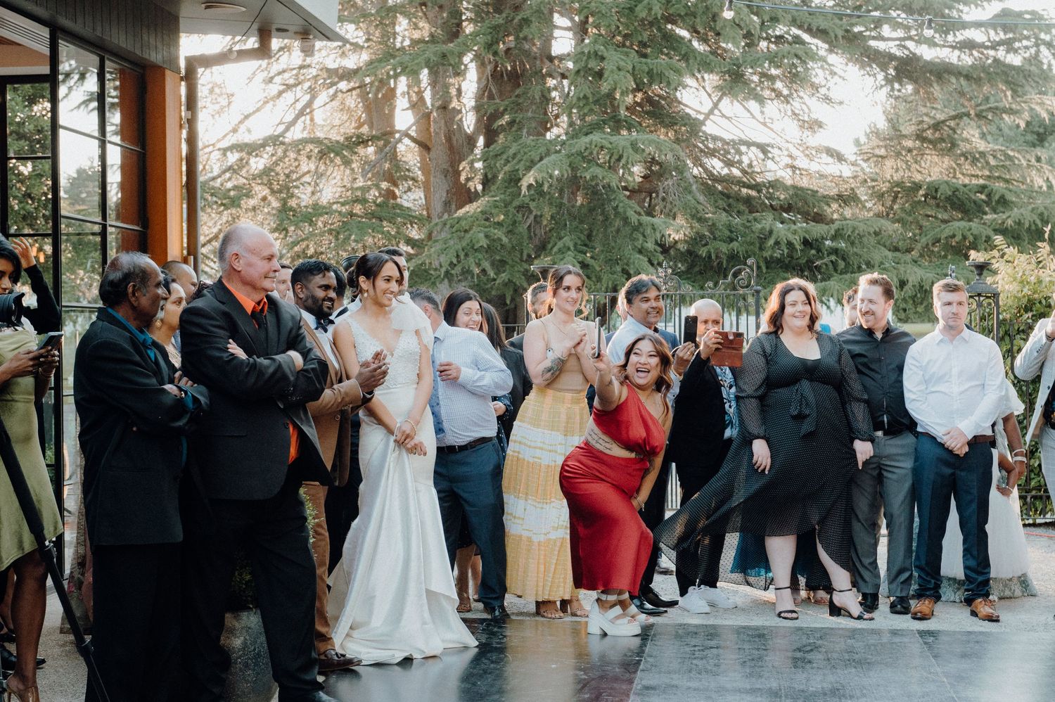 Wedding guests gathered outside watching entertainment during an outdoor celebration.