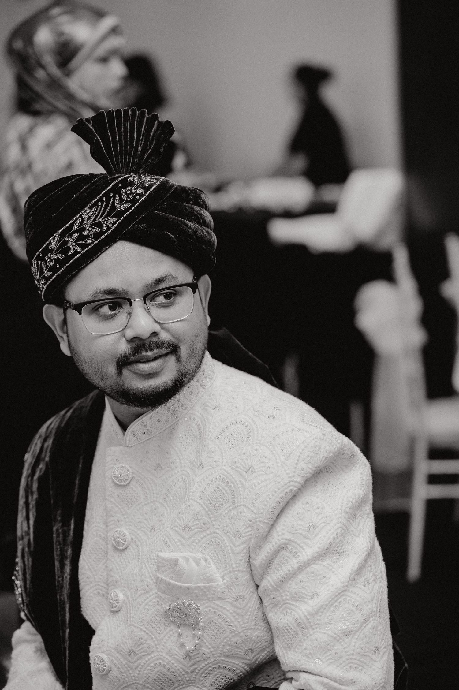 Traditional wedding attire featuring an ornate black and gold turban and white embroidered sherwani.