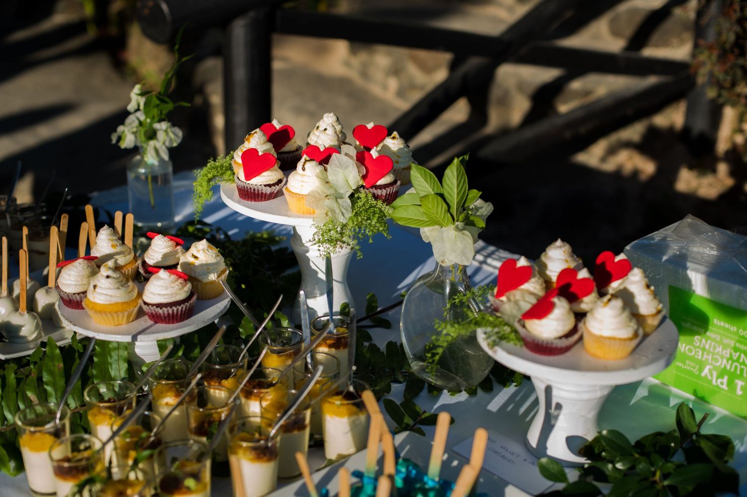 Dessert display featuring colorful cupcakes and strawberry treats on tiered stands.