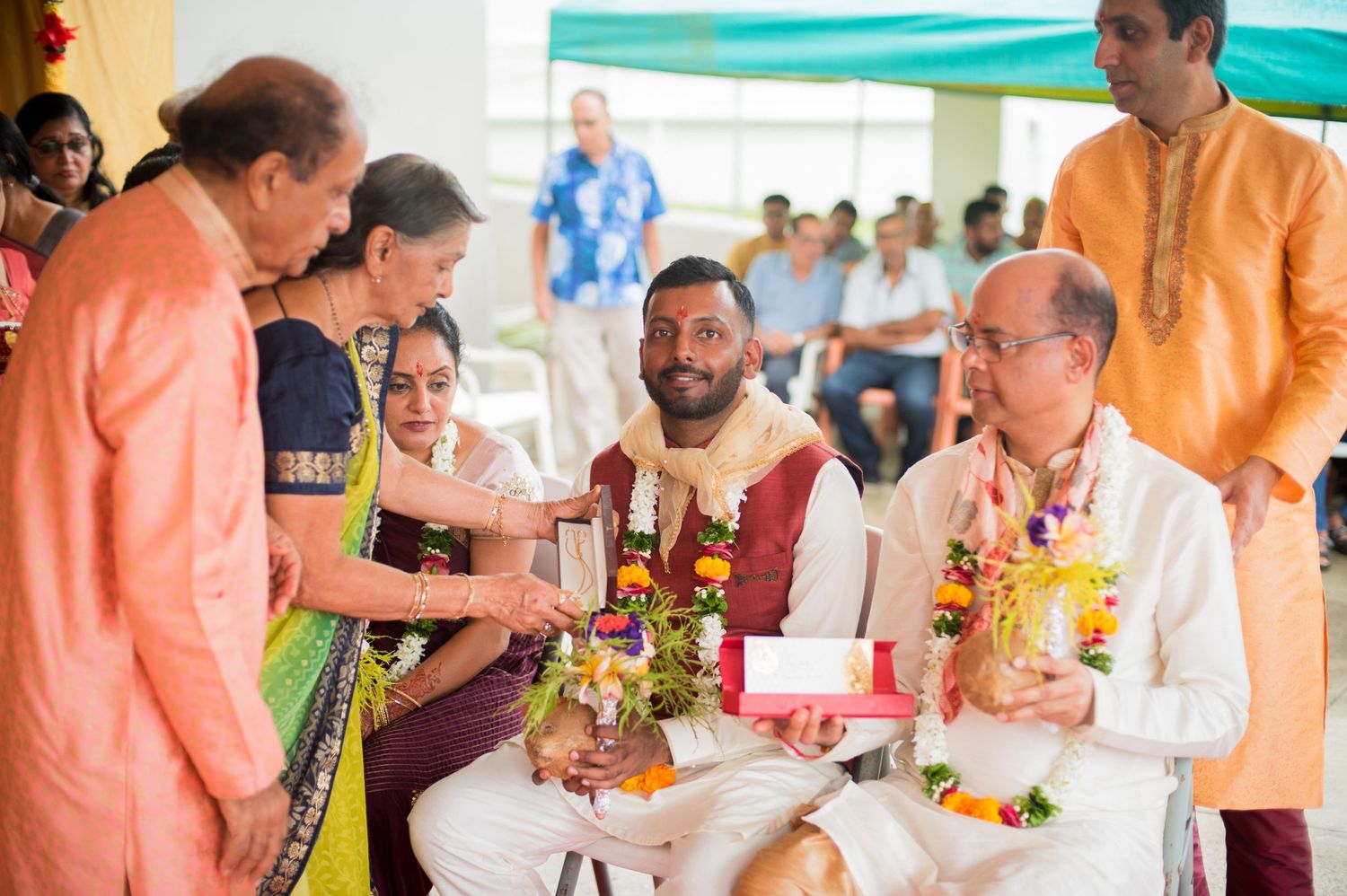People gathered around a table during a traditional Indian wedding ceremony with colorful decorations.