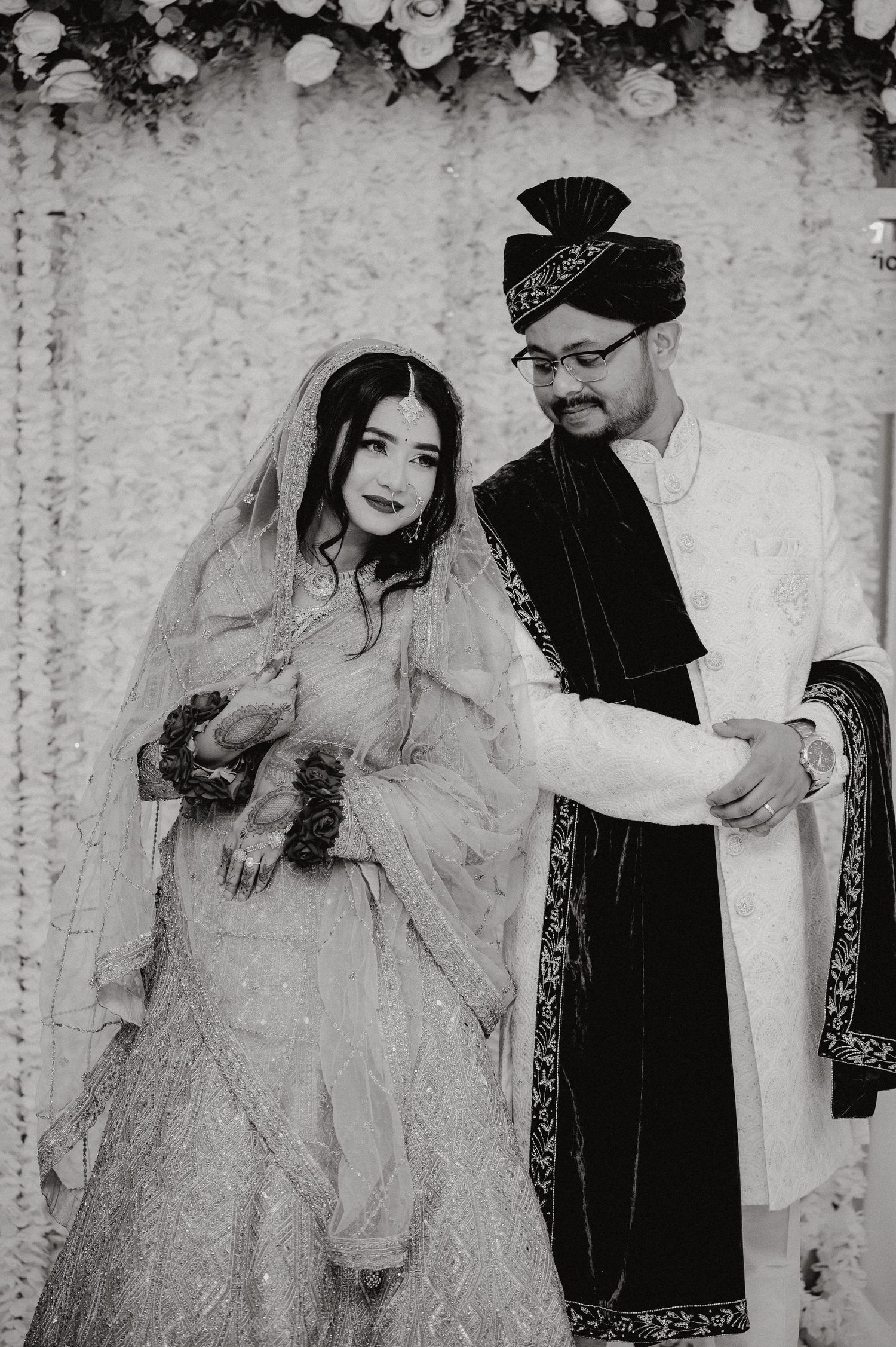 Black and white portrait of couple in traditional South Asian wedding attire.
