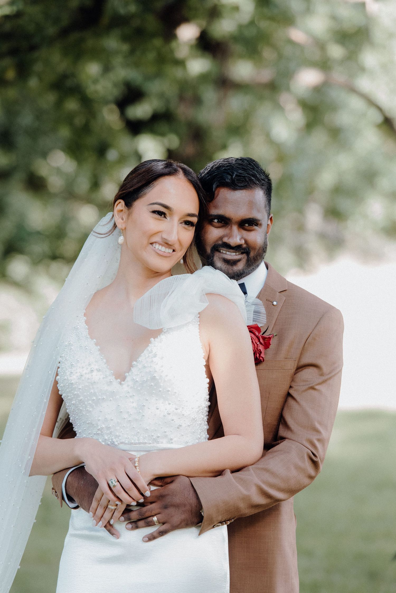 Newlyweds share intimate moment in garden setting wearing elegant wedding attire.