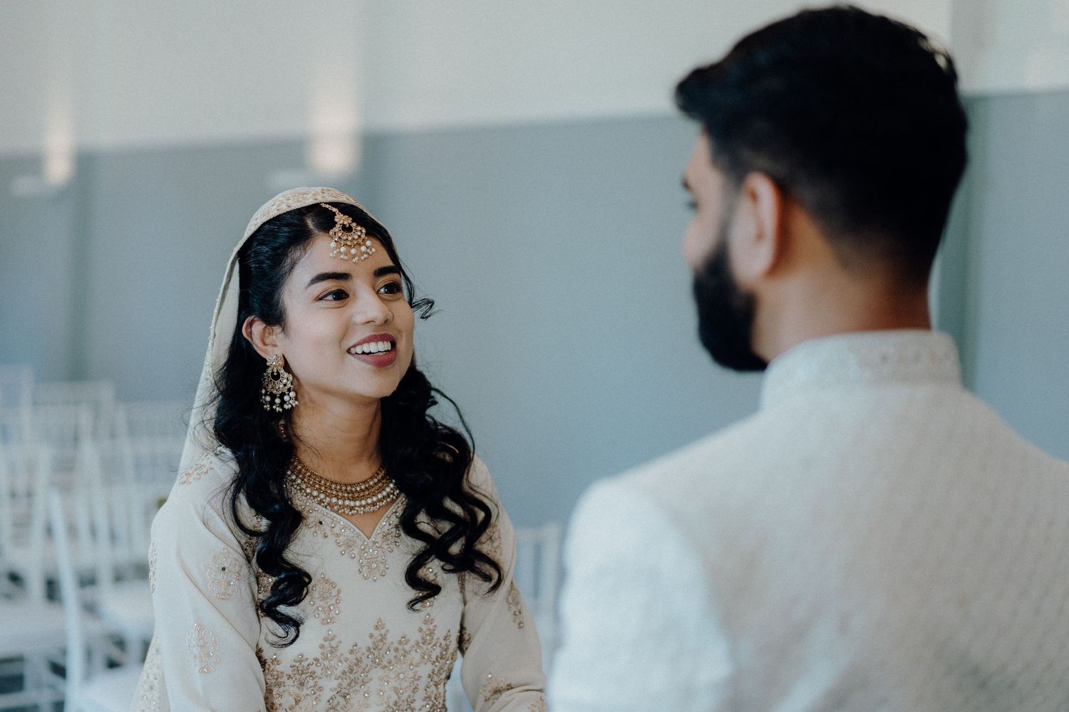 An intimate wedding moment in a light-filled ceremony space decorated with chandeliers.