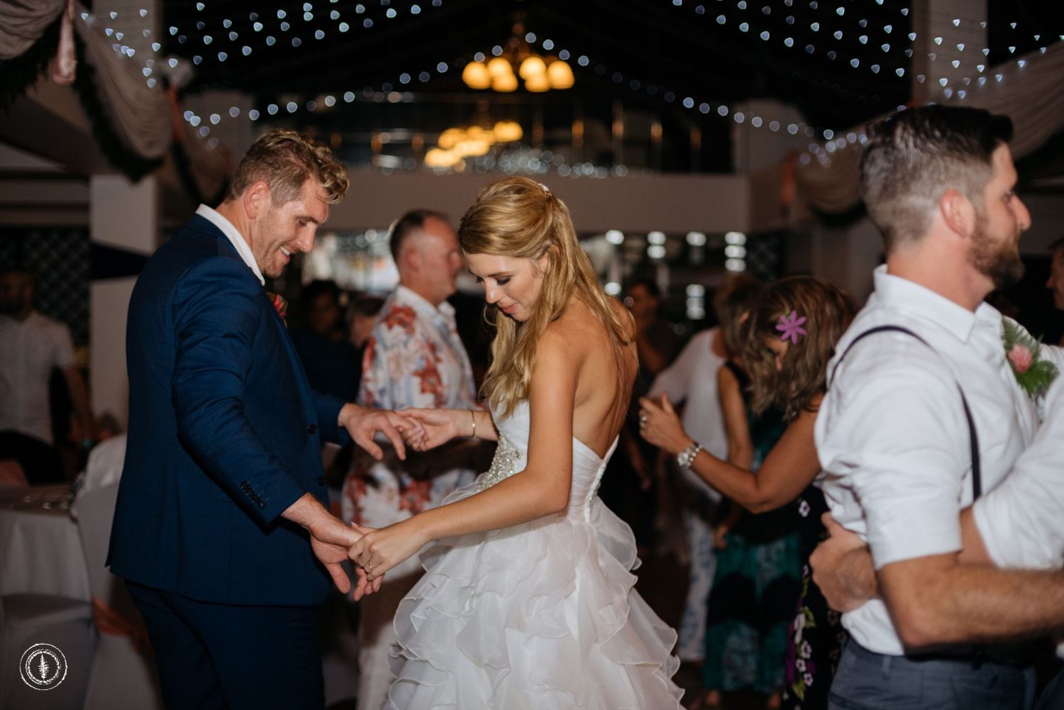 A couple dancing together at their wedding reception beneath string lights and elegant decor.