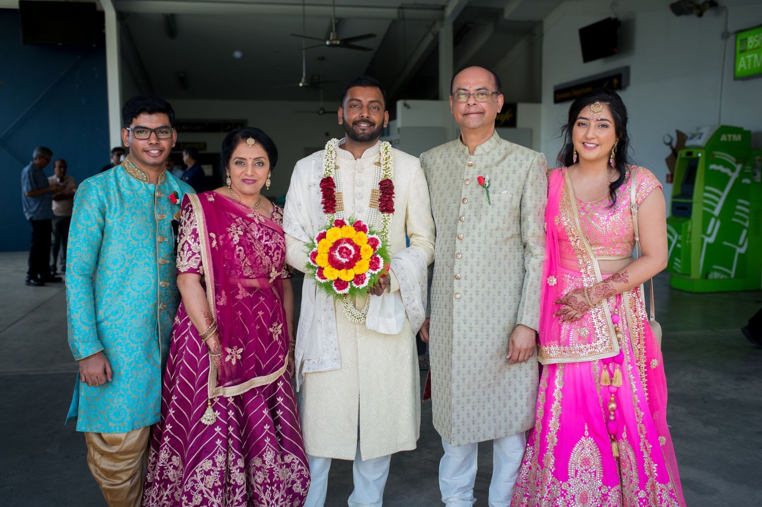 Group photo of people wearing colorful Indian formal attire posing indoors.
