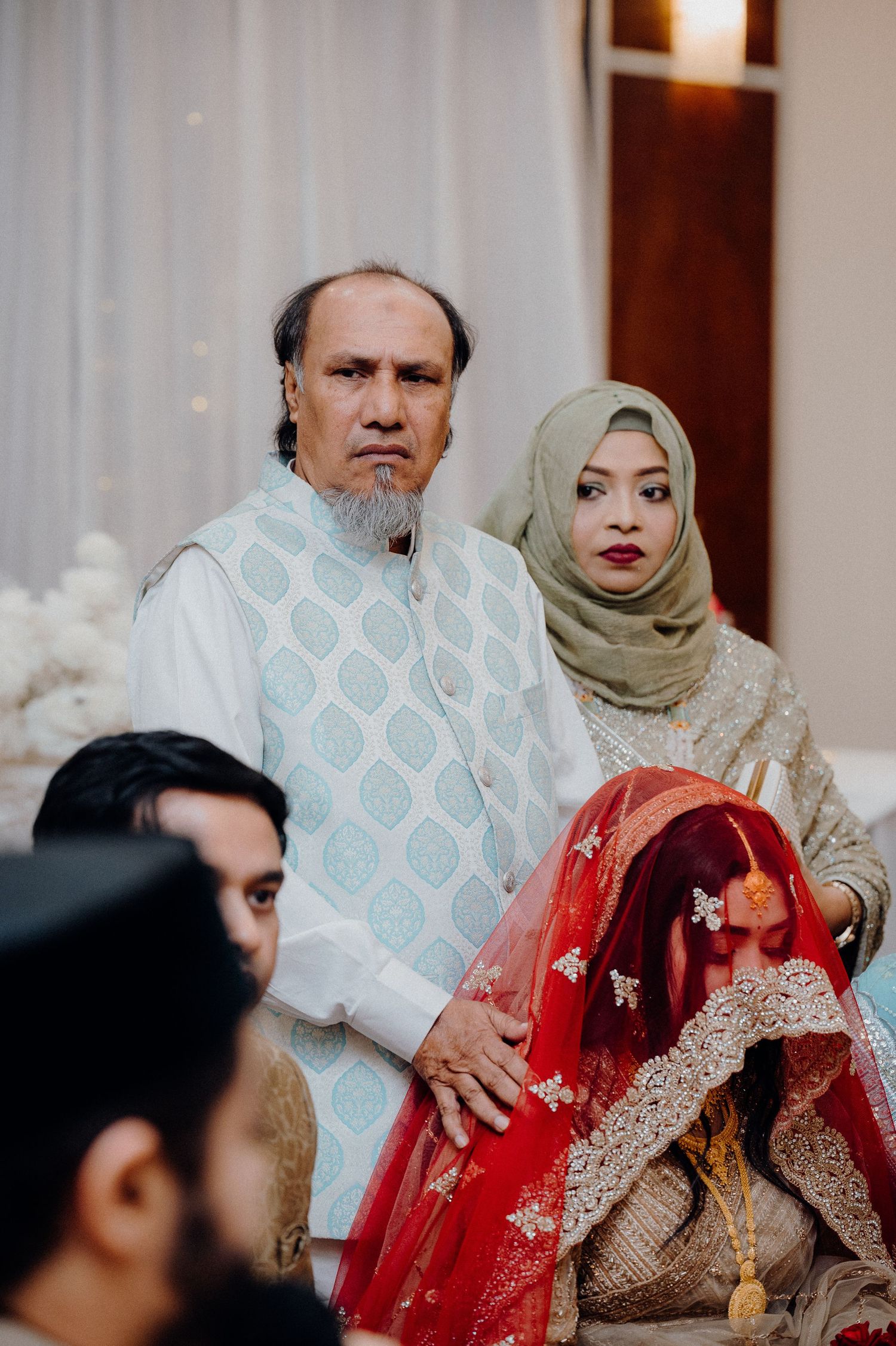 Traditional wedding ceremony with participants in formal cultural attire and hijab.
