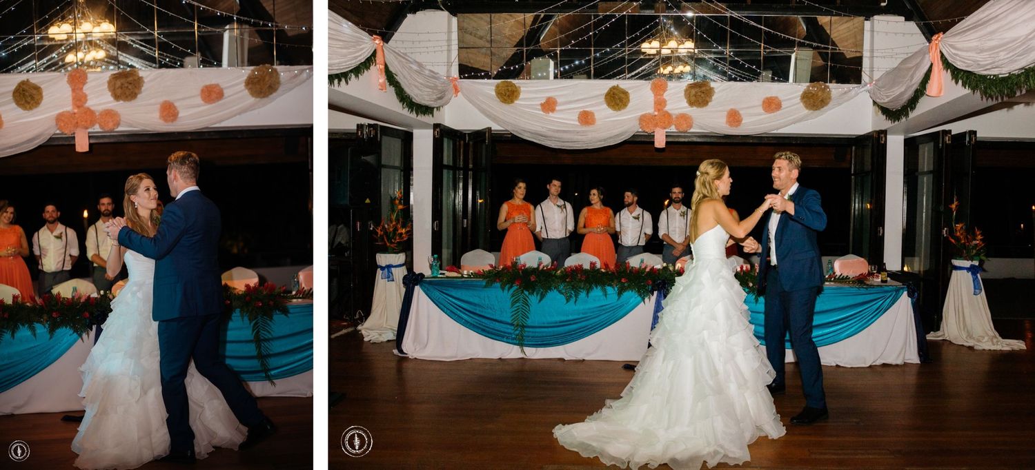 A couple dancing at their wedding reception with navy and white decor visible in the background.
