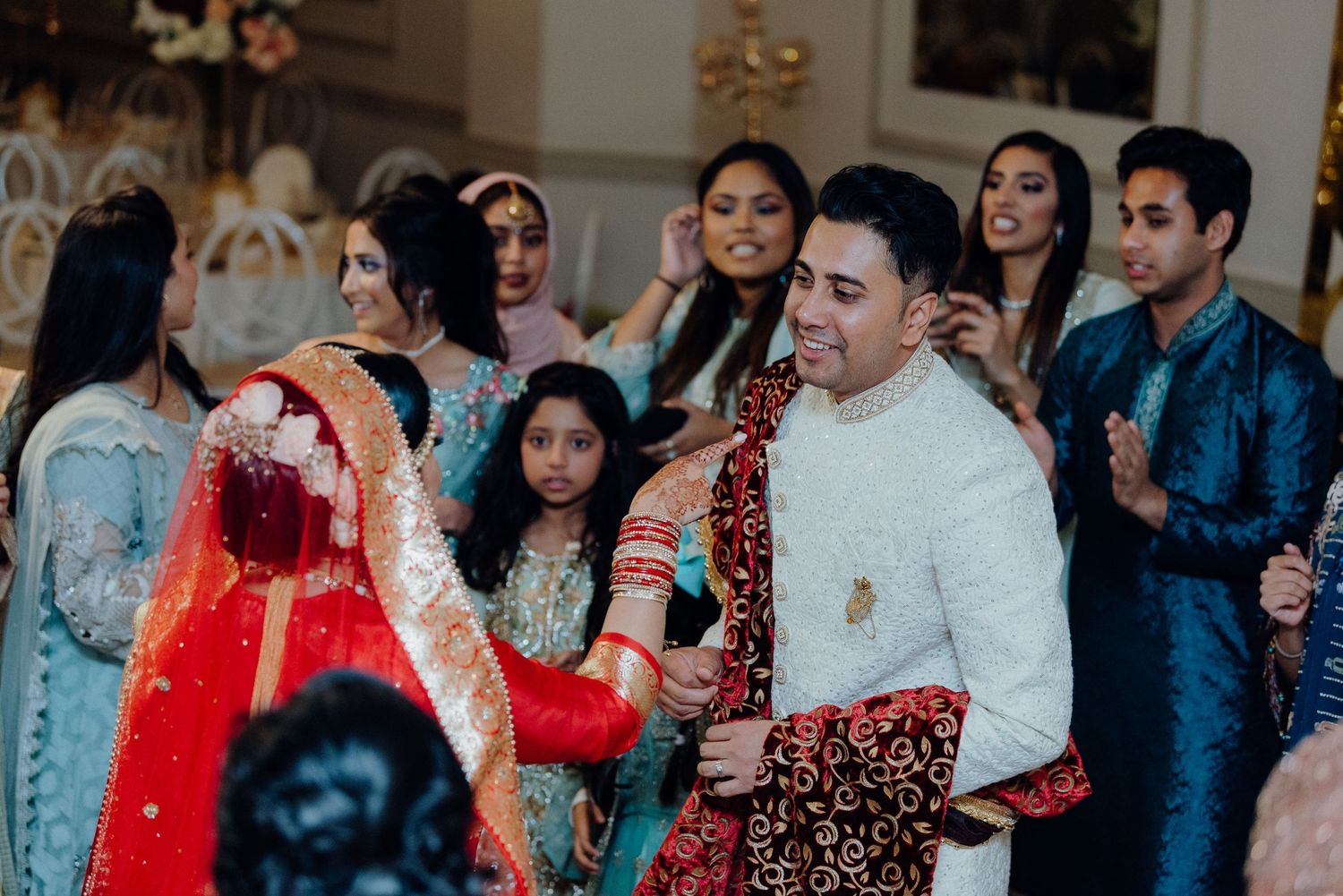 Wedding guests in traditional formal attire dancing and celebrating at an indoor reception.