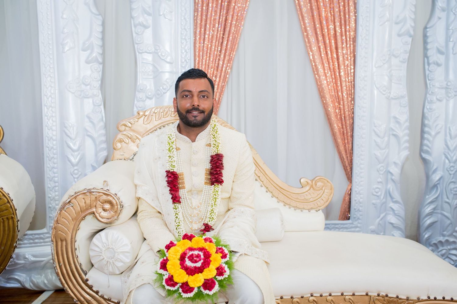Wedding venue setup with ornate throne-style seating and peach-colored drapery.