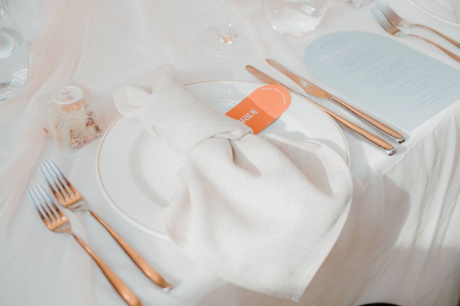 Elegant table setting with white napkin, gold cutlery, and place card at formal dining event.