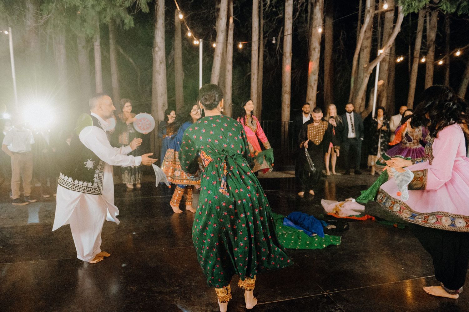 Traditional Indian wedding celebration with dancers in colorful attire under string lights.