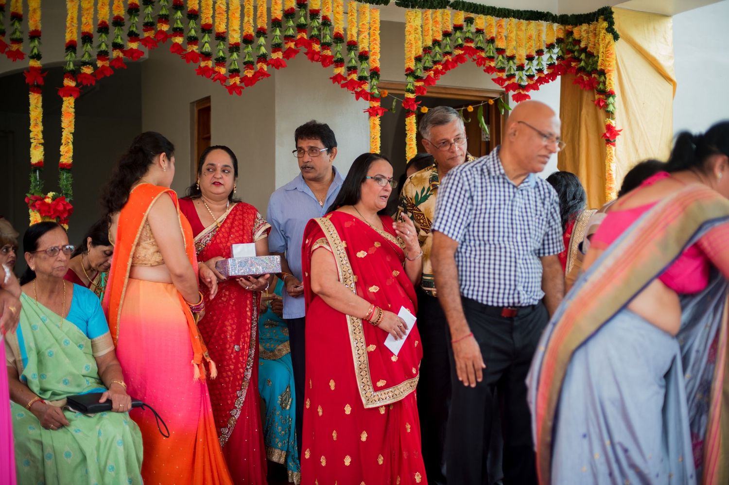 Wedding guests mingling under colorful decorative ceiling with geometric patterns at Indian celebration.