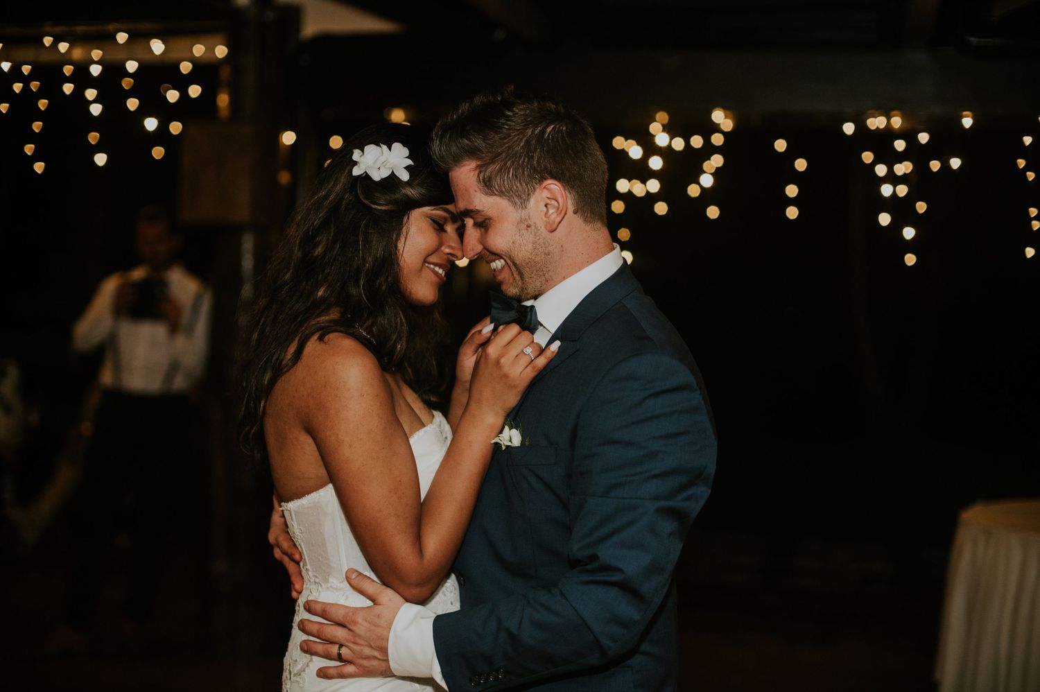An intimate moment shared during a wedding dance under sparkly fairy lights.