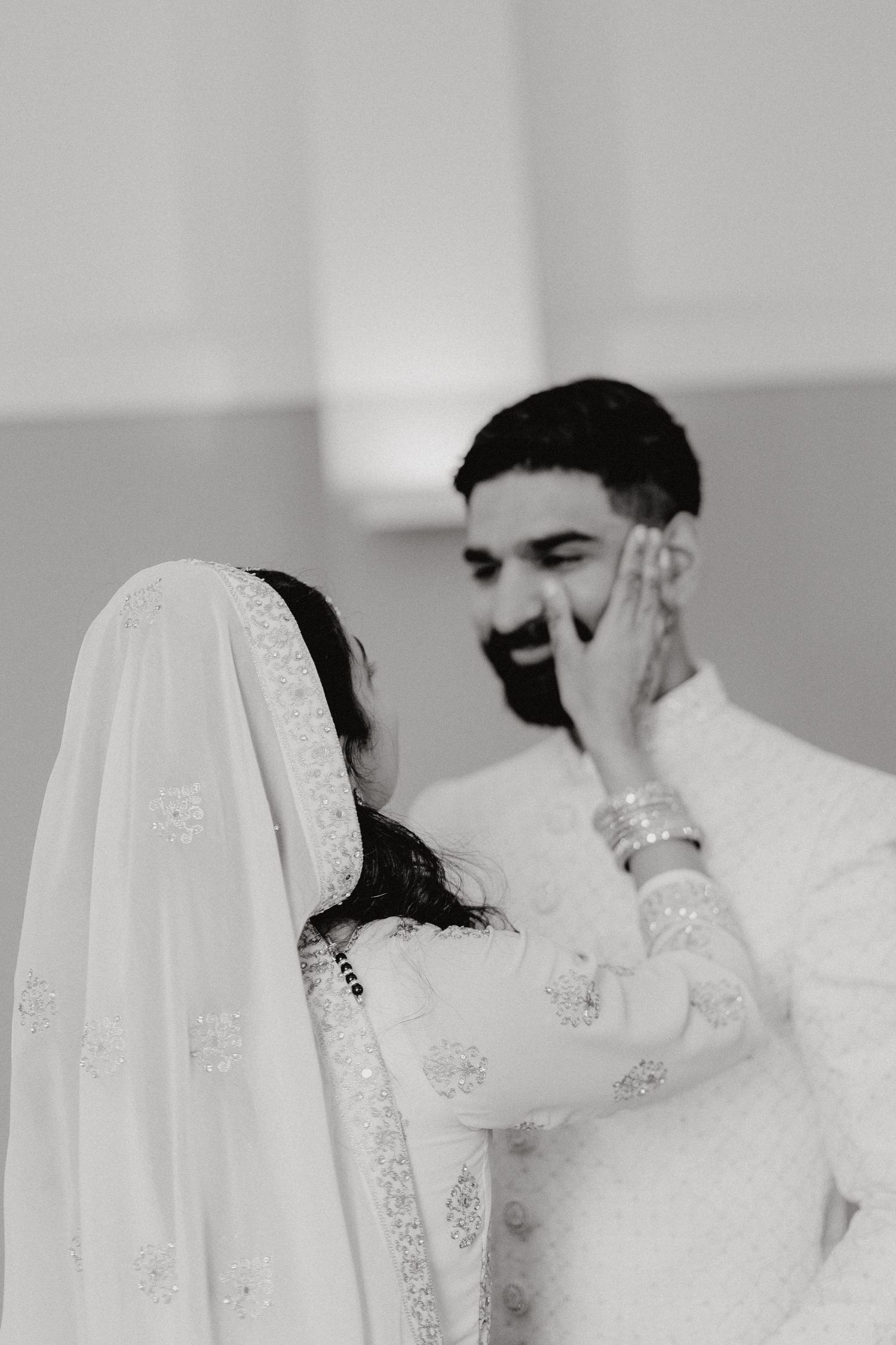 A tender black and white moment captured between a couple in traditional South Asian wedding attire.