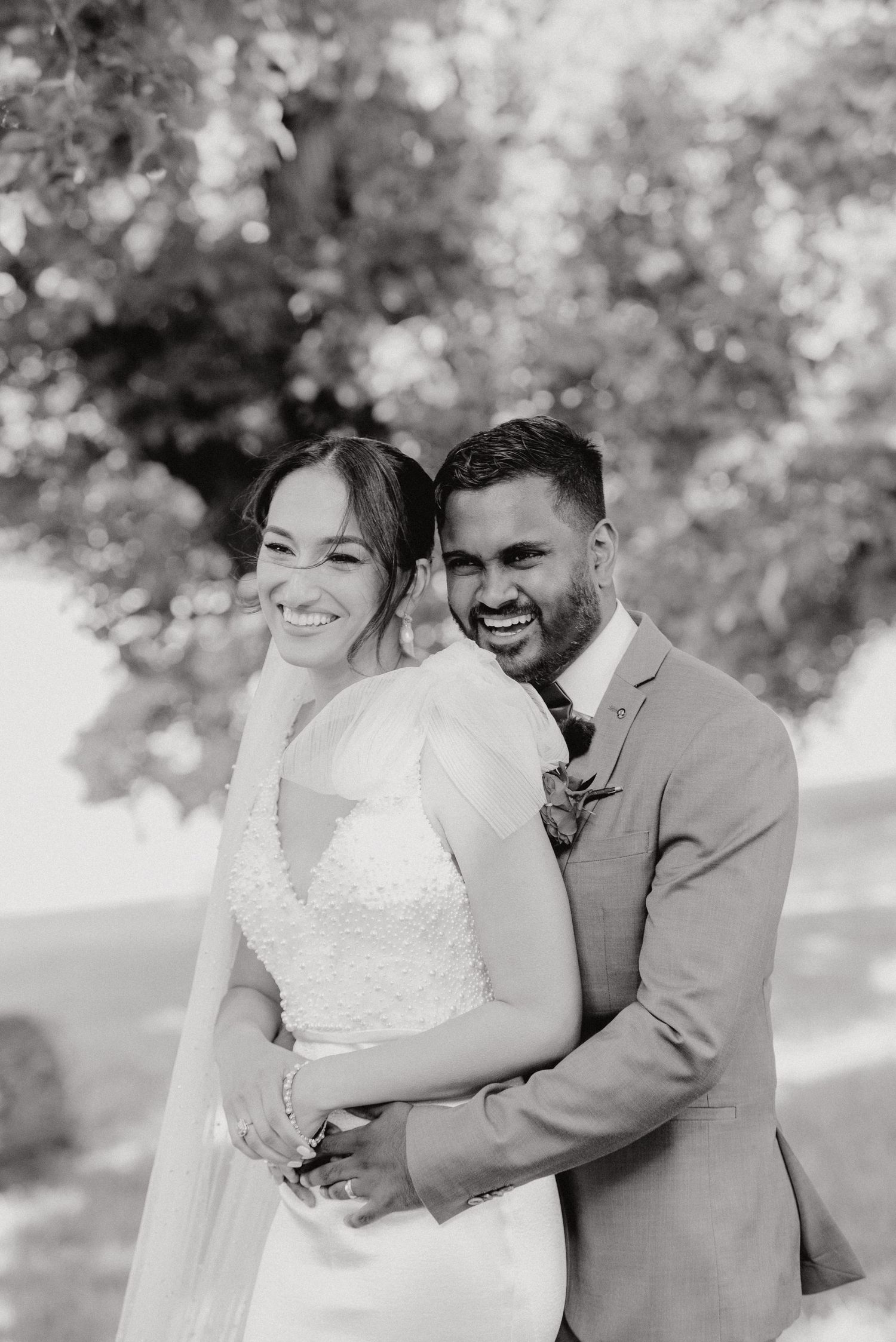 Black and white portrait of happy newlyweds embracing outdoors.