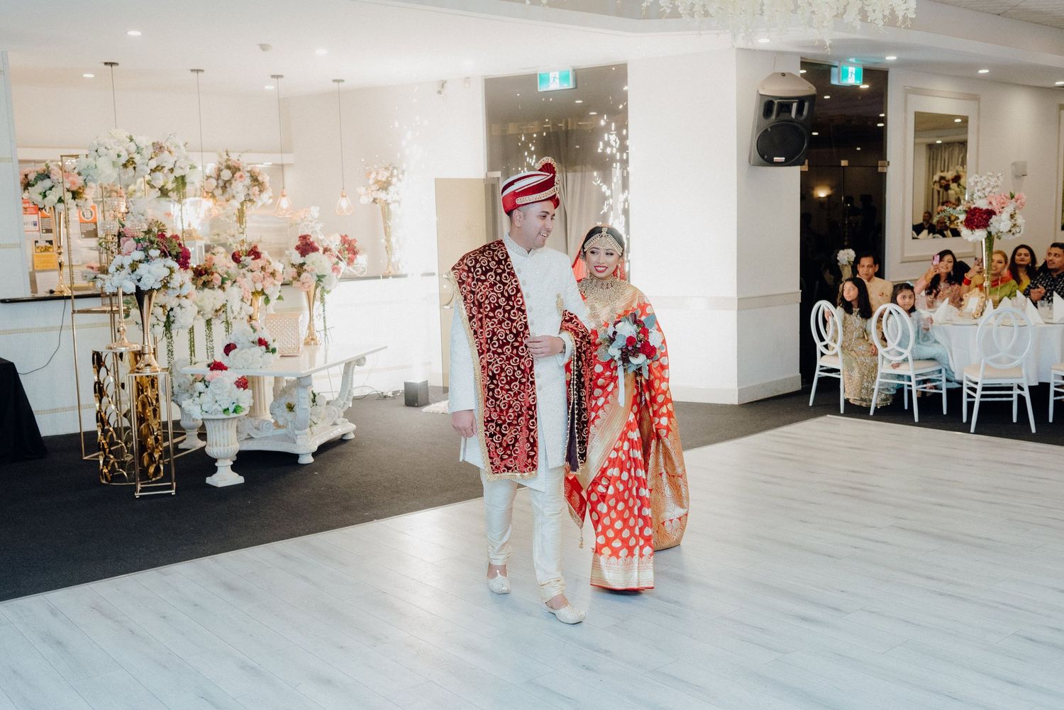 Traditional wedding ceremony in modern reception venue with elegant floral decorations.