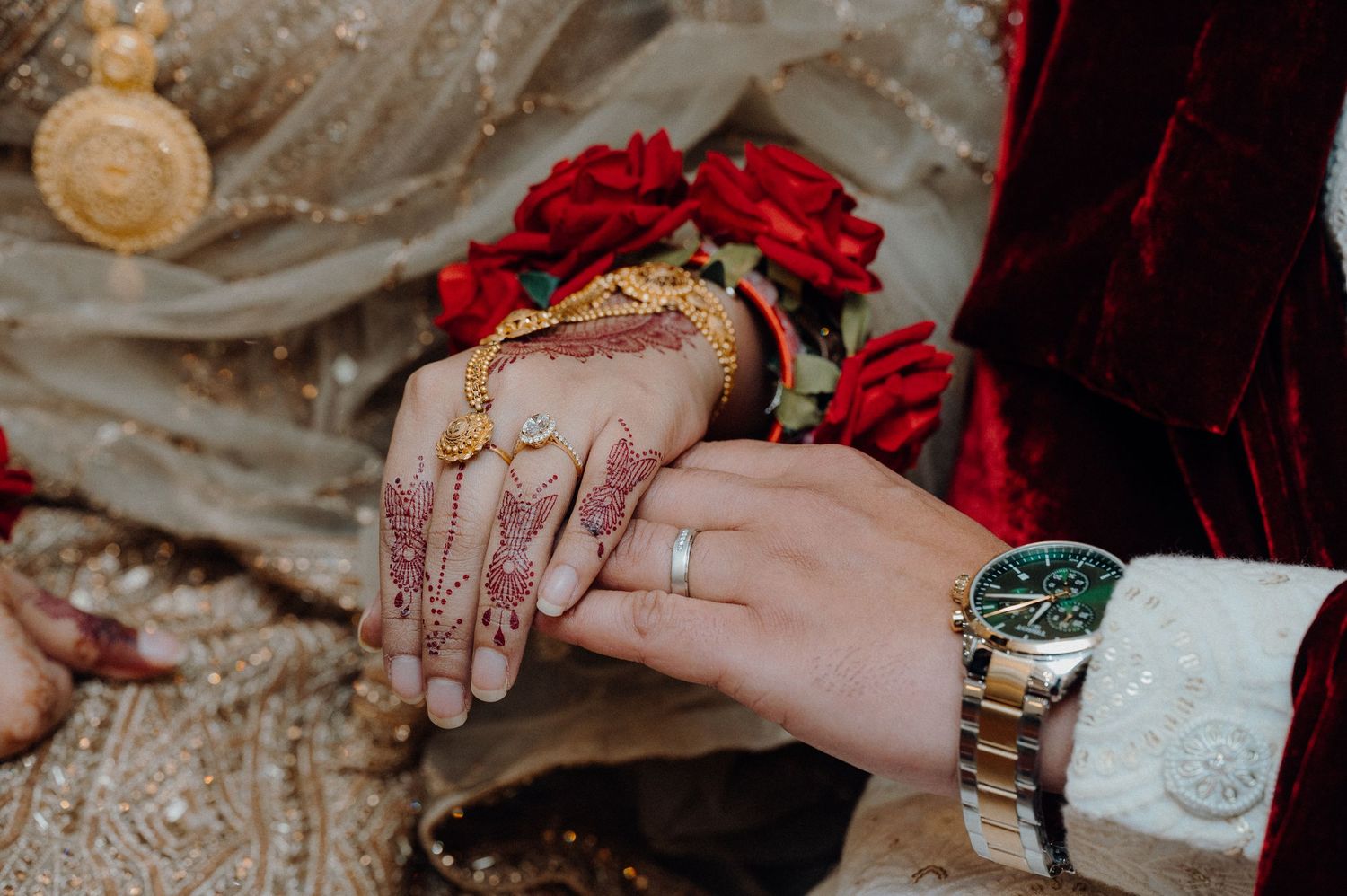 Close-up of hands with traditional henna designs exchanging rings during a wedding ceremony.