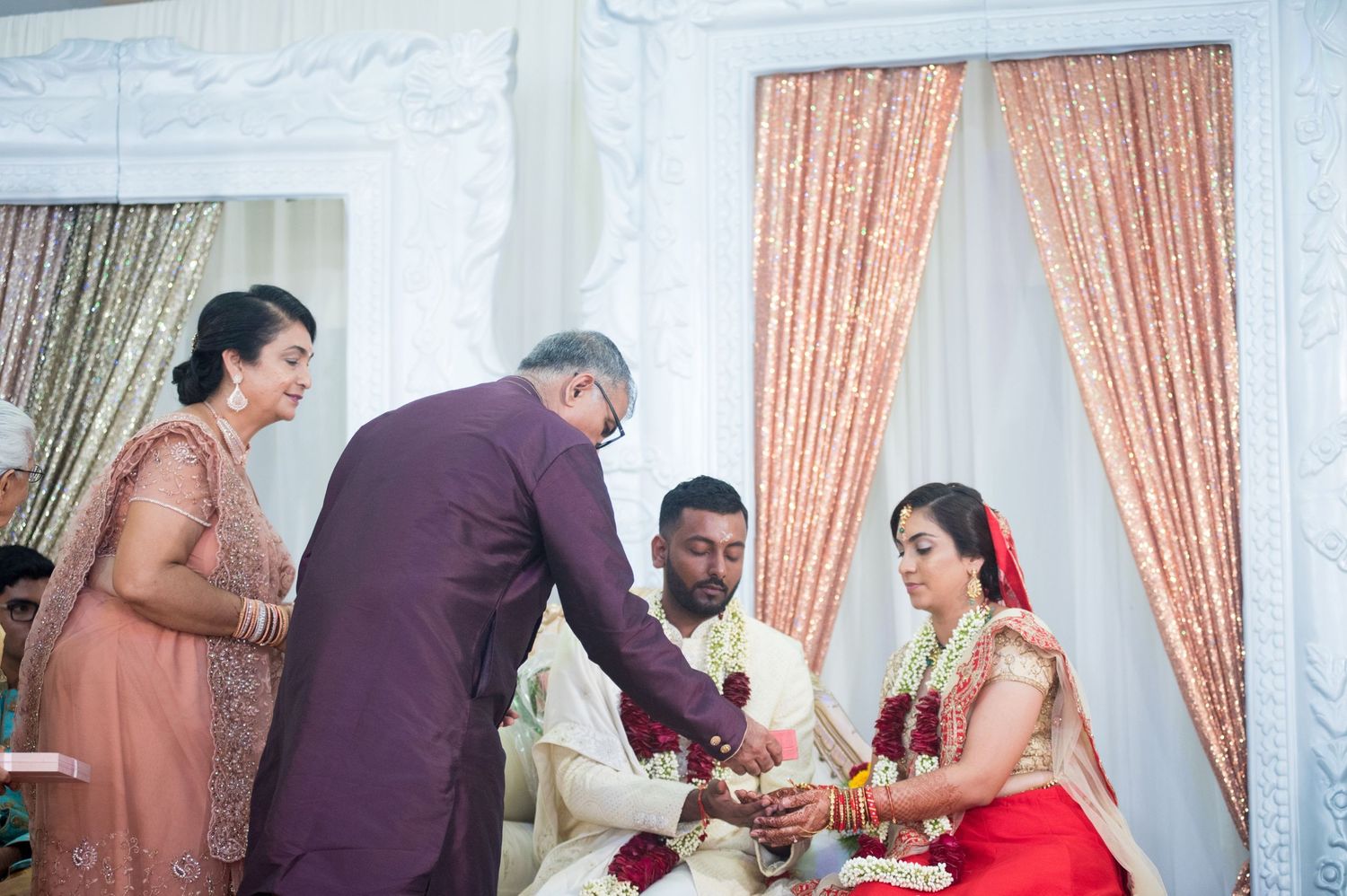 Traditional Indian wedding ritual being performed on a decorated white stage.