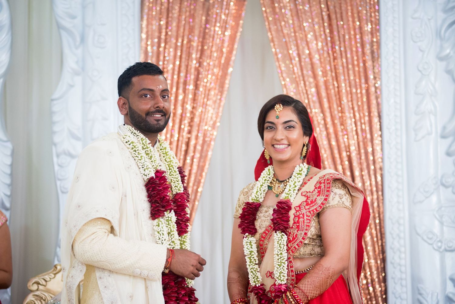 A couple in traditional Indian wedding attire exchanging vows during their ceremony.