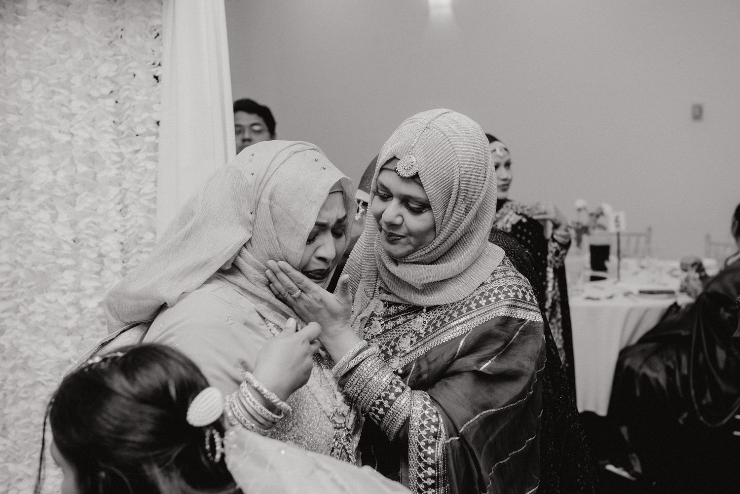 Black and white photo of guests sharing a joyful moment at a wedding celebration.