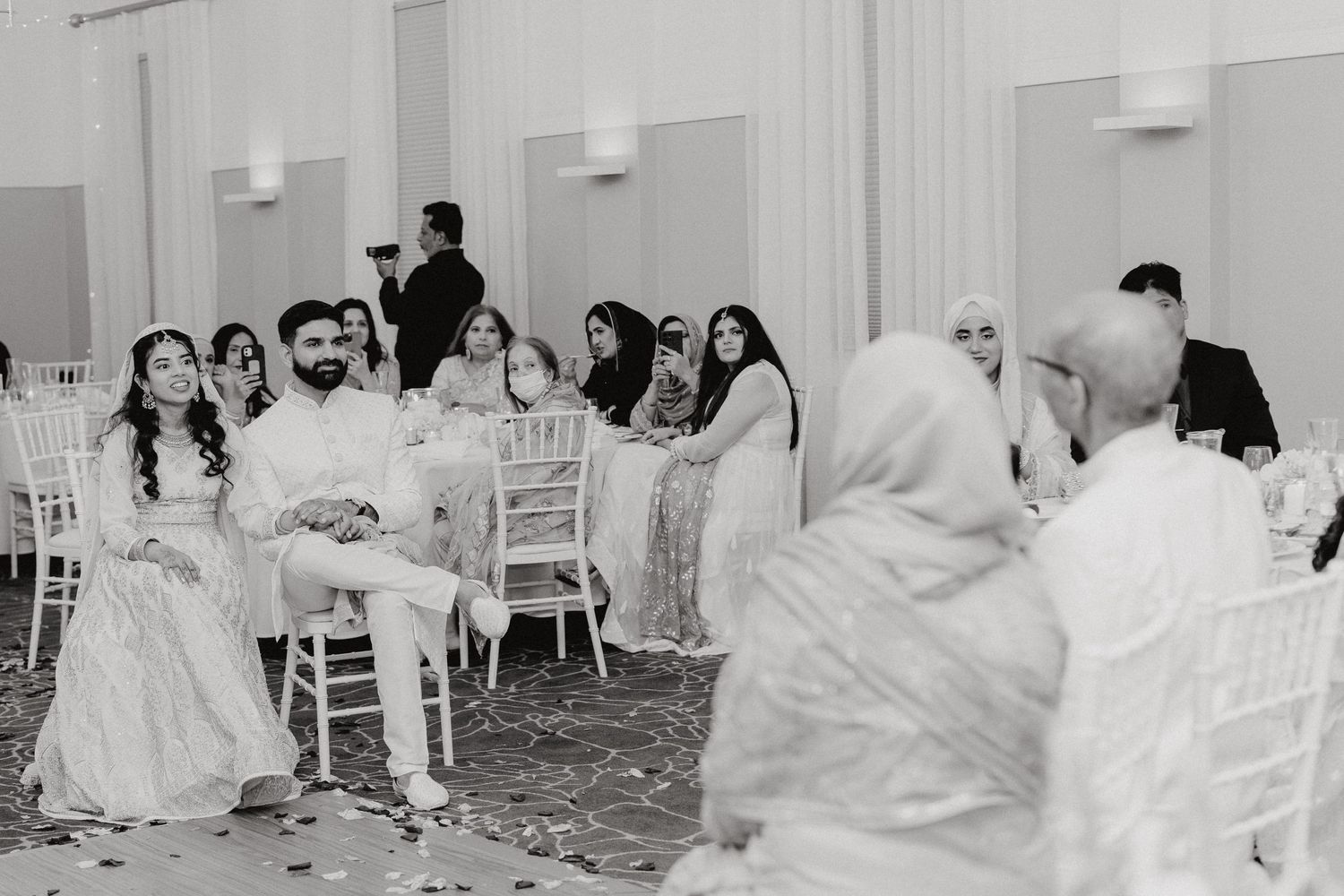 Wedding reception guests seated at tables in a banquet hall during celebrations.