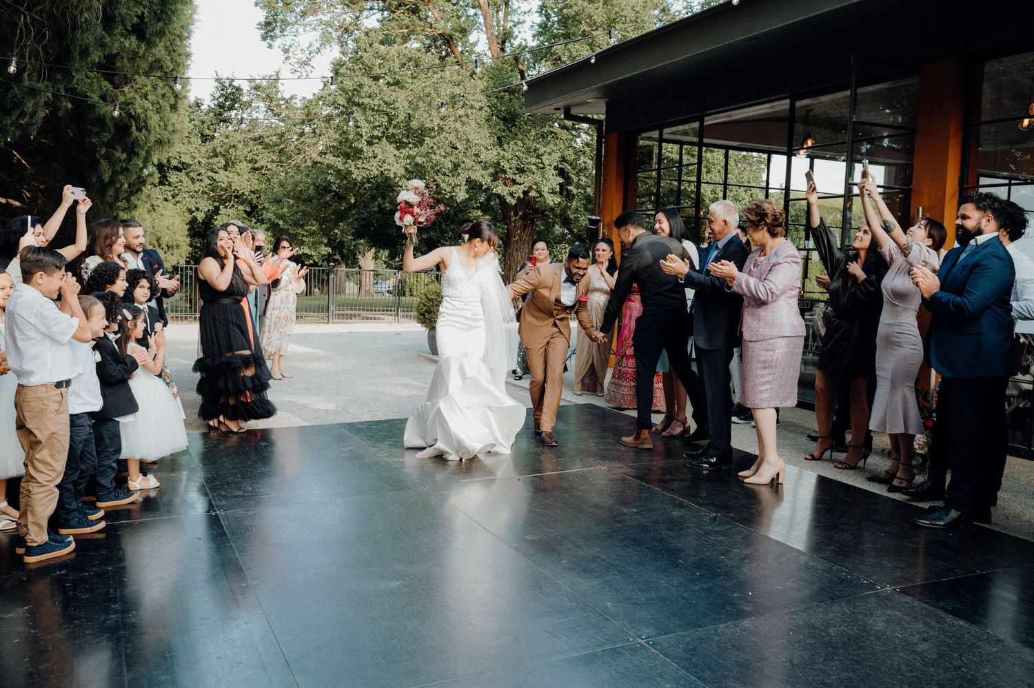 Wedding guests line both sides of an outdoor dance floor as newlyweds celebrate their first dance.