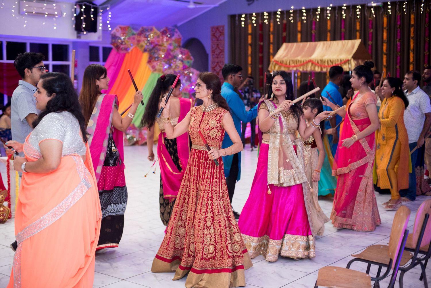 Guests in colorful traditional Indian attire dancing and celebrating at a wedding reception.